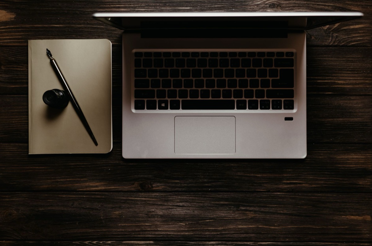 computador e caderno em mesa de madeira